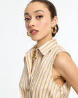 Woman wearing a beige and brown striped sleeveless blouse with gold earrings on a white background