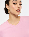 Woman wearing a pink sweater against a plain background