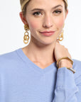 Woman wearing gold hoop earrings and a light blue sweater on a white background