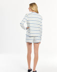 Woman wearing a white and blue striped cardigan standing against a white background