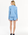 Woman showcasing a light blue look, photographed on a crisp white studio background.