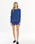 Woman wearing a blue long-sleeve top and shorts on a white background