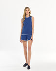 Woman wearing a blue sleeveless top and shorts set on a white background