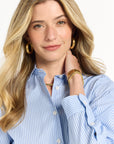 Woman wearing a blue striped shirt with jewelry on a white background