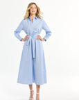 Woman wearing a light blue dress with a belt on a white background