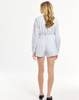 Woman wearing a blue and white striped shirt and shorts on a plain background