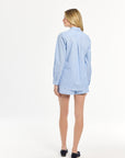 Woman wearing a light blue striped top and matching shorts on a white background
