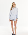 Woman wearing a light blue striped shirt and dark shoes on a white background