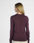 Back of a woman wearing a purple sweater on a white background
