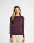 Woman wearing a purple long-sleeve top against a white background