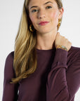 Woman wearing a purple long-sleeve shirt against a white background