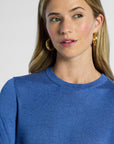 close up shot of a woman wearing a blue sweater with a plain background