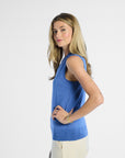 side profile of a woman wearing a blue sleeveless silk top on a white background