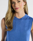 Woman wearing a blue sleeveless silk top against a white background