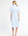 Woman wearing a light blue dress with a belt on a white background