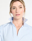 Woman wearing a light blue striped shirt against a white background