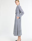 Woman wearing a long, striped dress with a belt on a white background