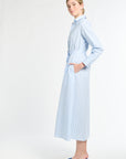 Woman wearing a light blue dress with a belt on a white background