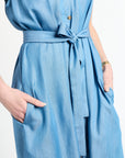 Woman wearing a light blue dress with buttons and tie around the waste