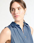 Woman wearing a sleeveless denim shirt against a white background