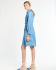 Woman standing to the side modeling long sleeve blue dress with heels