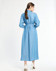 Woman standing modeling a long blue dress against a white background