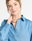 Woman wearing a blue blouse with buttons with a plain white background