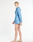 Woman modeling blue shorts and a blue long sleeve top against a white background