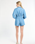 Woman wearing blue shorts and long sleeve top on a white backdrop