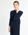 Woman wearing a navy blue sweater and pants on a white background