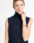 Woman wearing a navy sleeveless sweater against a white background