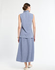 Woman wearing light blue sleeveless sweater with matching light blue knit skirt.