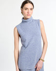 Woman with blue sleeveless knit on with white background.