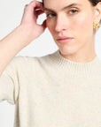 Woman wearing a cream sweater against a light background