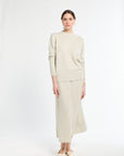 Woman wearing a beige sweater and skirt set on a white background