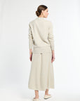 Woman wearing a beige sweater and skirt set on a white background