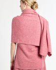 Woman wearing a pink shawl over a dress on a white background