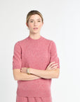 Woman wearing a pink sweater against a white background