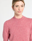 Woman wearing a pink sweater against a white background