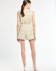 Back of woman wearing golden and light blue tweed sleeveless top and shorts on white background