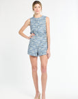 Woman wearing a sleeveless blue tweed top and shorts on a white background