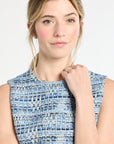 Woman wearing a blue tweed sleeveless top against a white background