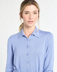 Woman wearing a light blue shirt with a belt against a white background