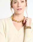 Woman wearing a gold chain necklace and bracelet against a white background