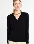 Woman wearing a black sweater and gold necklace on a white background