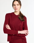 Woman wearing a burgundy outfit with a matching cardigan and skirt on a white background