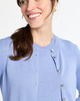 Woman wearing a light blue cardigan with a plain background