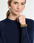 Woman wearing a navy sweater with a gold bracelet on a white background