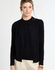 Woman wearing a black blouse and beige pants on a white background