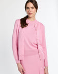 Woman wearing a pink outfit with a matching jacket and skirt on a white background